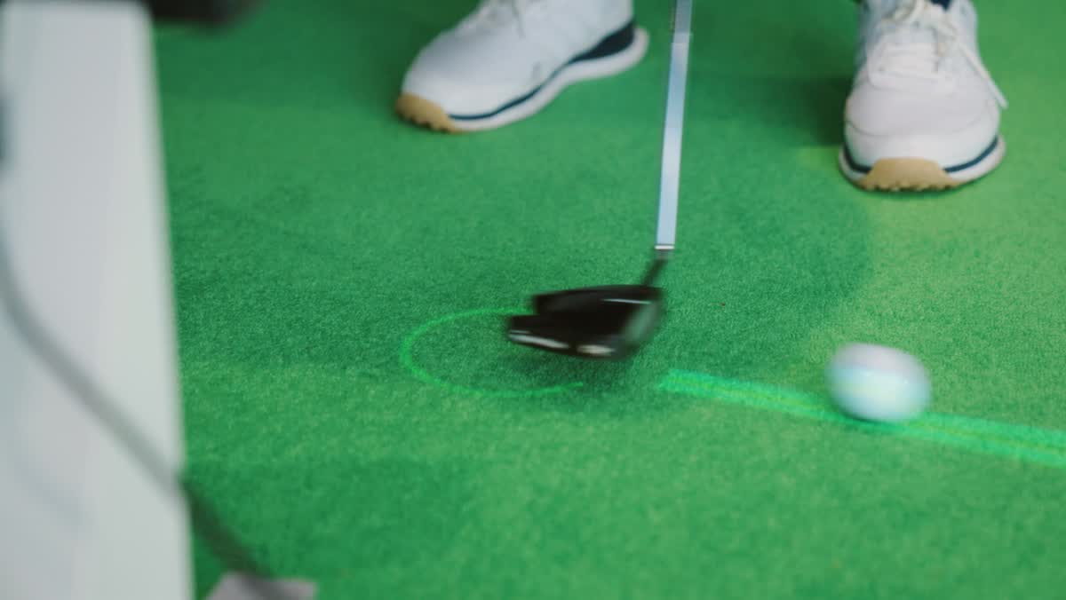 Laser line projected on the putting surface beside a putter and ball